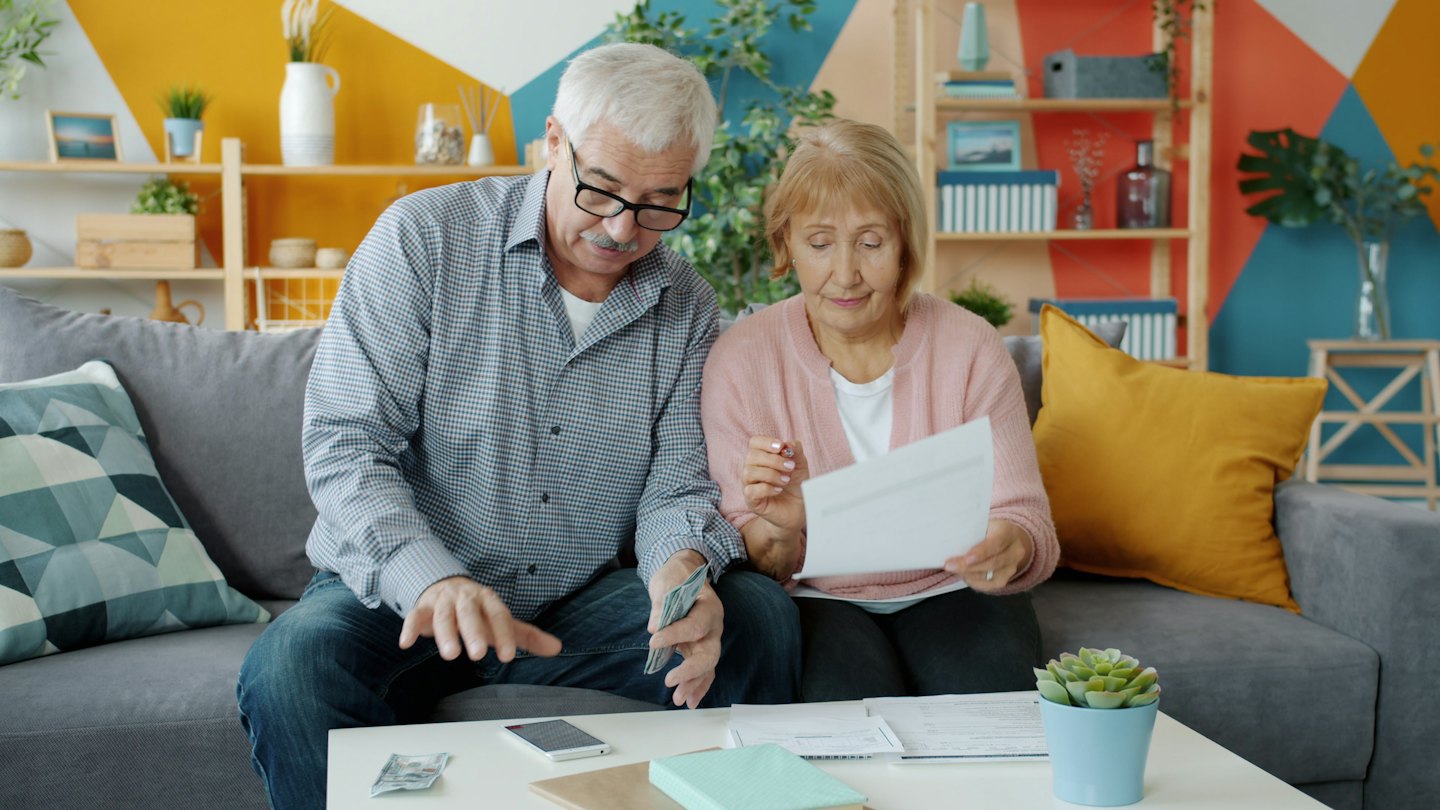 Elderly couple managing finances at a coffee table.